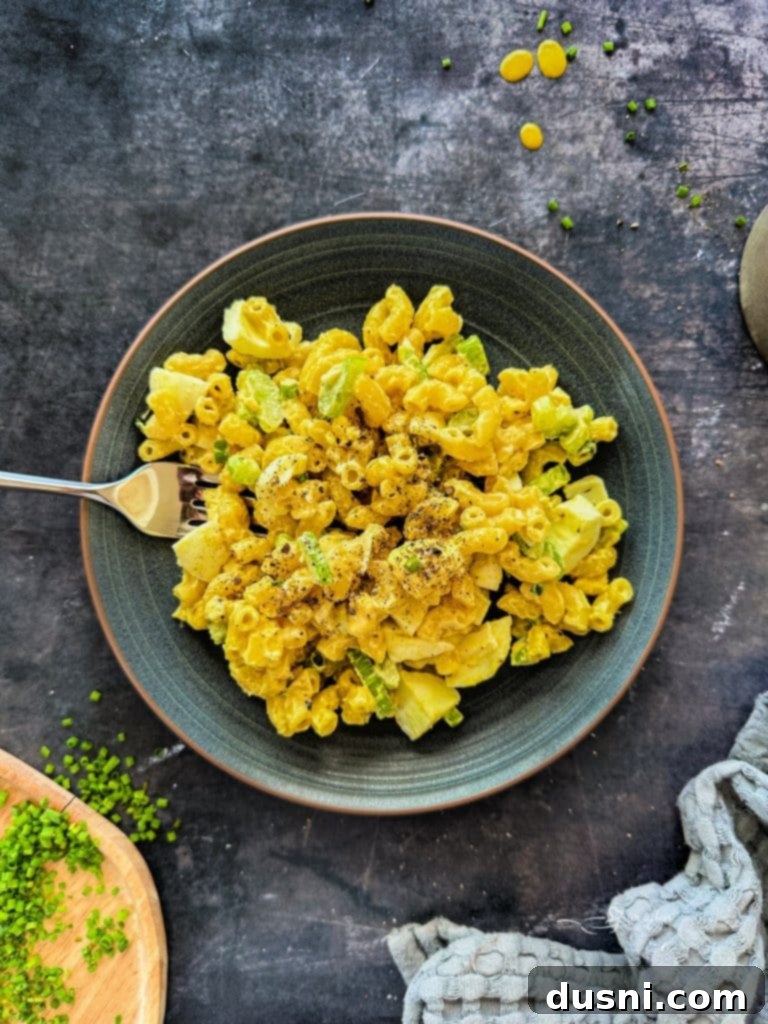Ingredients for macaroni salad laid out on a table: cooked pasta, chopped celery, green onions, and hard-boiled eggs.