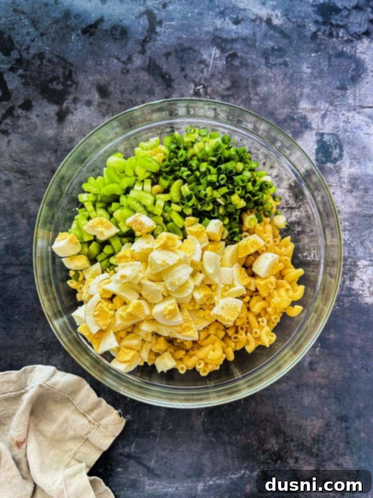 Chopped hard-boiled eggs being added to a bowl.