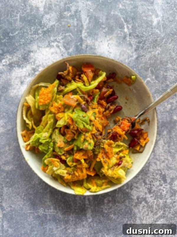 Ultimate Doritos Taco Salad 11 A large bowl of Doritos Taco Salad with a serving spoon, showcasing its fresh ingredients and vibrant colors in a rustic setting.