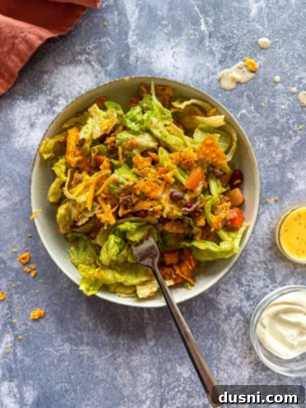Ultimate Doritos Taco Salad 12 Close-up of the taco salad showing fresh ingredients like lettuce, tomatoes, and cheese, in a rustic bowl.