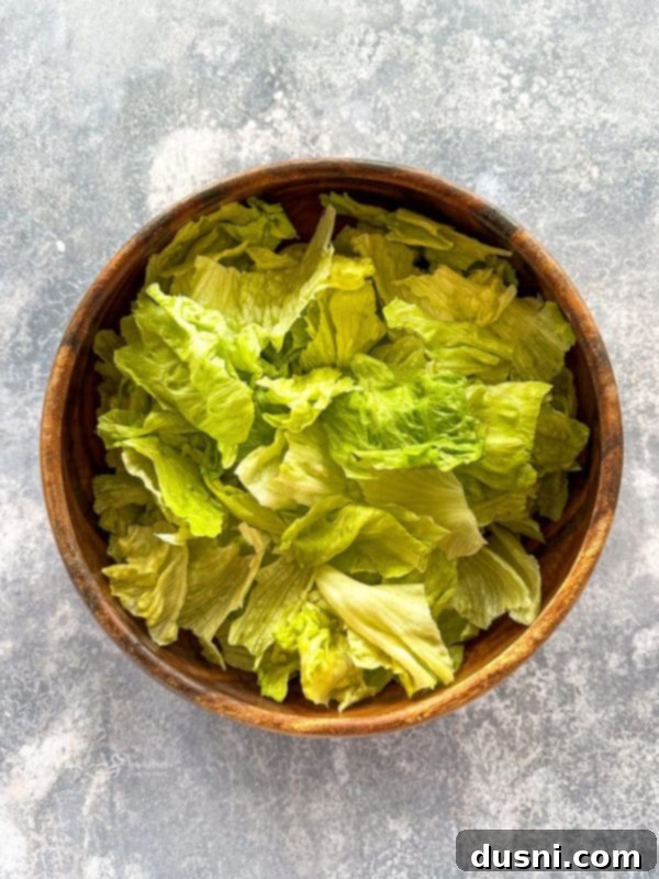 Ultimate Doritos Taco Salad 7 Tossing the taco salad ingredients in a large bowl with salad tongs, showing the fresh mixture.