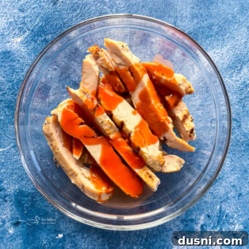 Assembling buffalo chicken pizza with sauce, chicken, onions, and cheese