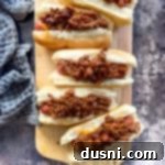 Hot dogs with chili on them on a wood board