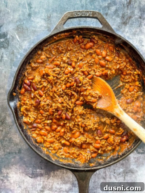 Chili simmering in a skillet with tomato sauce and beans