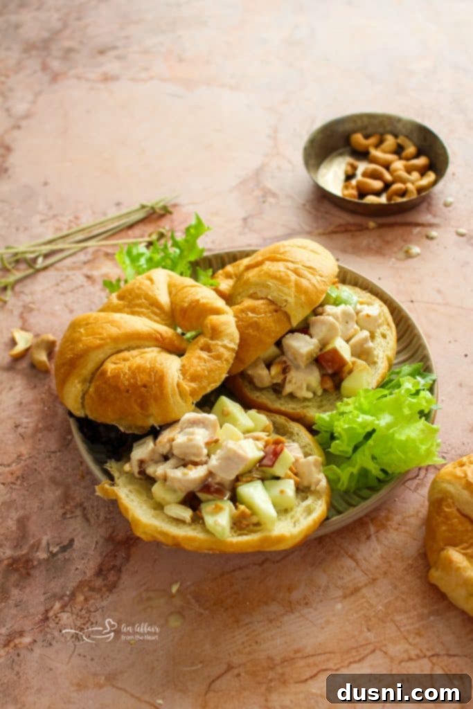 A bowl of Apple Chicken Salad garnished with fresh herbs and served with crackers.