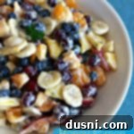 fruit salad in a white bowl with text "Honey Lemon Fruit Salad"