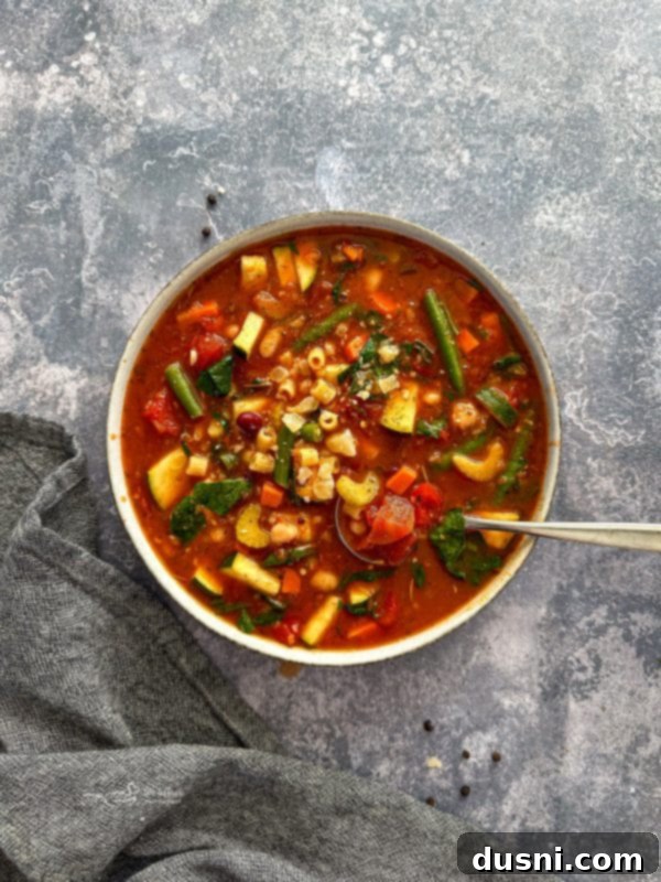 Simmered Garden Minestrone 13 A serving of minestrone soup garnished with parmesan and fresh parsley.