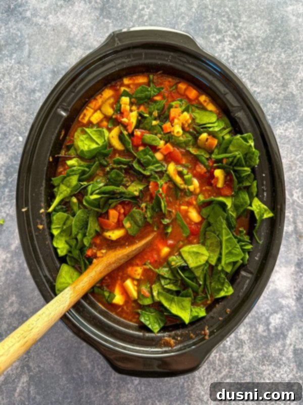 Simmered Garden Minestrone 10 Third step of cooking crock pot minestrone: stirring in green beans and spinach.