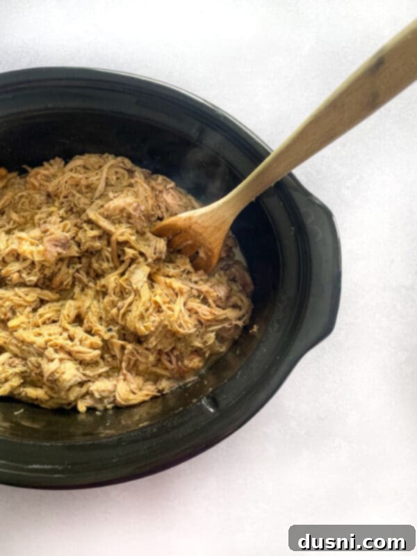 Crispy Tender Slow Cooker Carnitas 2 Slow Cooker Carnitas on a plate with fresh cilantro and lime