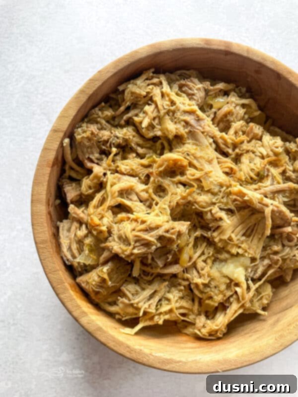 Crispy Tender Slow Cooker Carnitas 16 Slow Cooker Carnitas on a serving plate with cilantro and lime