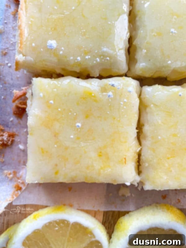 four lemon brownies with lemons, showing the chewy texture and bright glaze