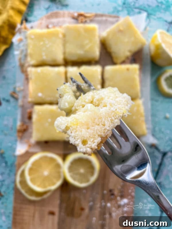 close-up view of a single lemon brownie square on a fork, showing the texture and glaze
