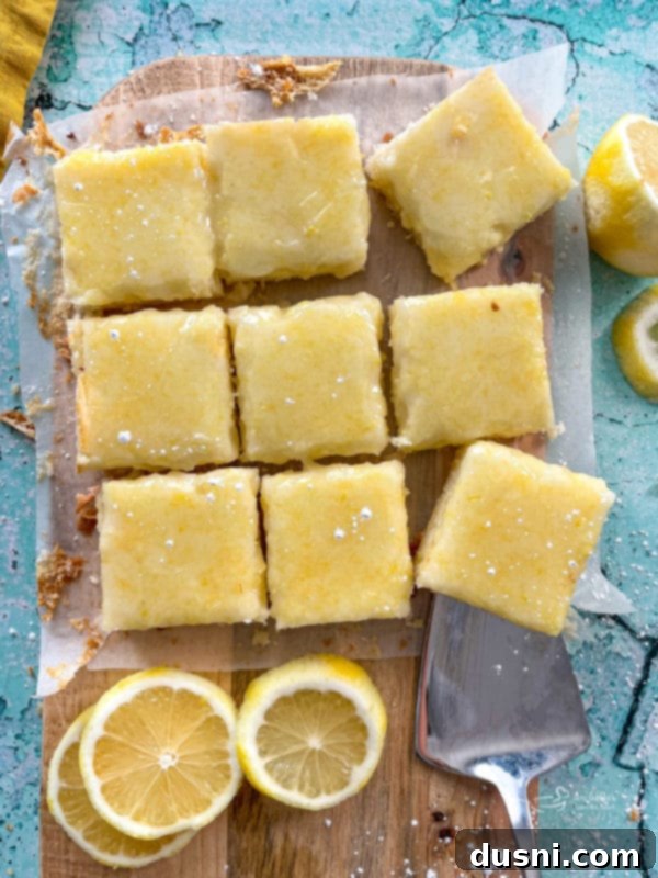 top view of lemon brownies on cutting board with fresh lemons, highlighting their golden color and glaze