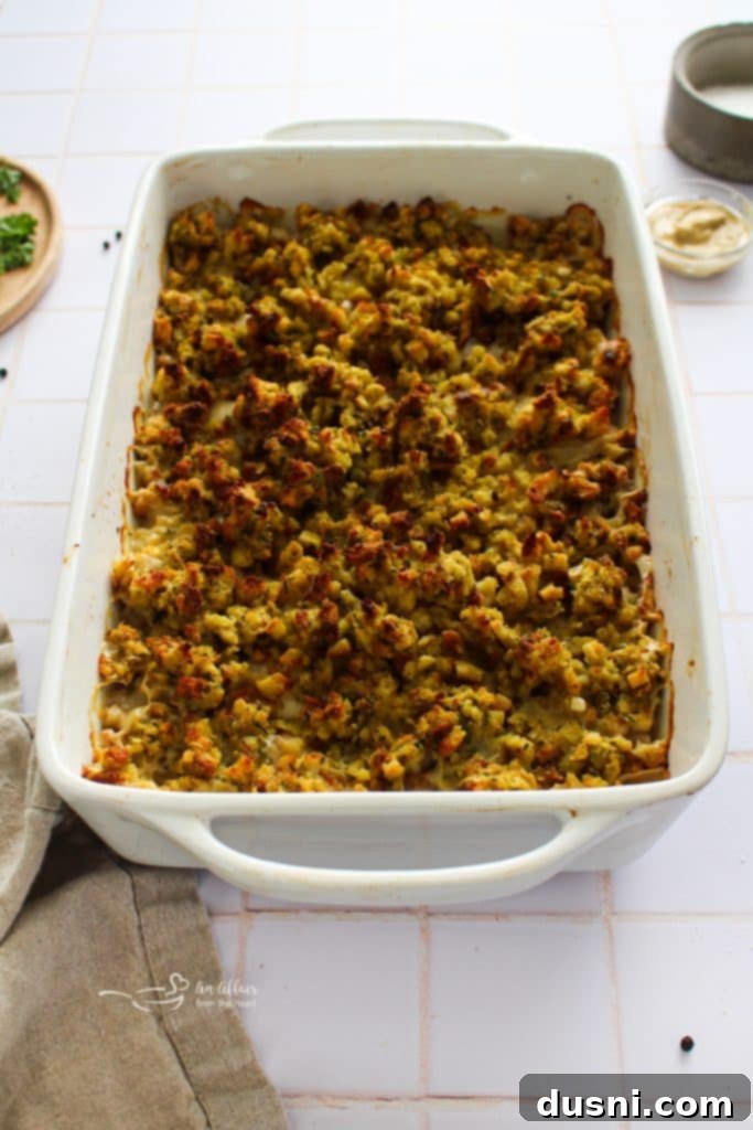 Creamy Chicken Cordon Bleu Bake 8 Step-by-step image showing the assembled casserole with chicken, ham, Swiss cheese, and stuffing topping in a baking dish, ready for the oven.