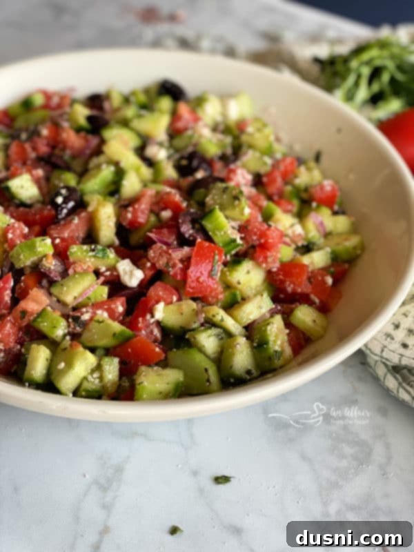 Hellenic Cucumber Medley 11 Side view of a white bowl filled with a colorful Greek cucumber salad, showcasing the texture and freshness of ingredients.