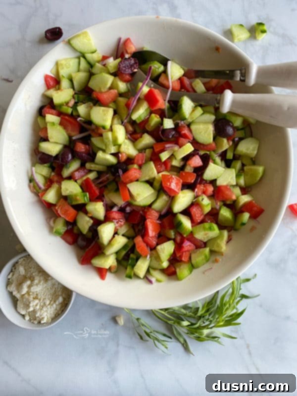 Hellenic Cucumber Medley 5 Top view of chopped cucumbers, tomatoes, and Kalamata olives freshly combined in a large white mixing bowl.