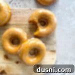 Glazed Baked Pumpkin Donuts with a bite taken out, showing the moist interior.
