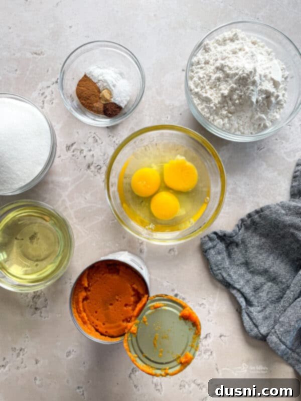 A collection of ingredients laid out for making Glazed Baked Pumpkin Donuts, featuring pumpkin puree, spices, flour, and baking essentials.