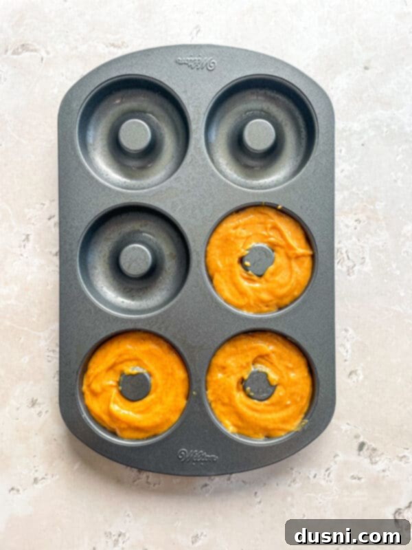 Spoon about 3-4 Tablespoons of donut batter into each donut section of a baking pan.