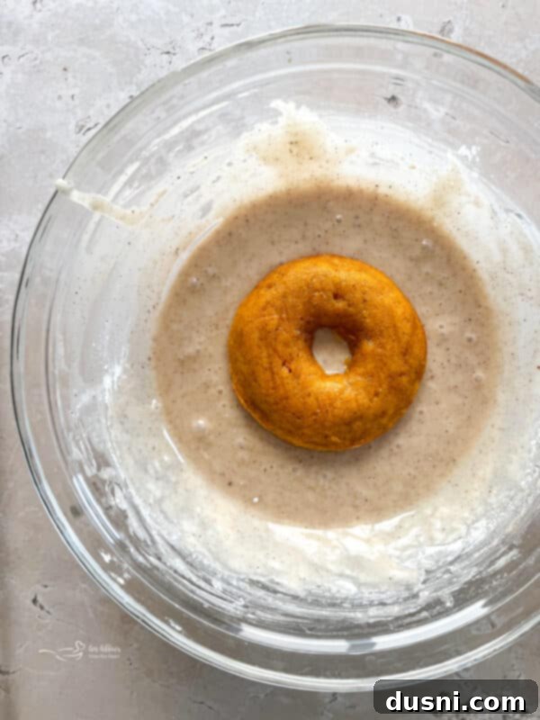 Spiced Glaze ingredients being whisked together in a bowl before dunking baked donuts.