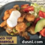 Taco Tot Casserole on a blue plate, garnished with fresh cilantro