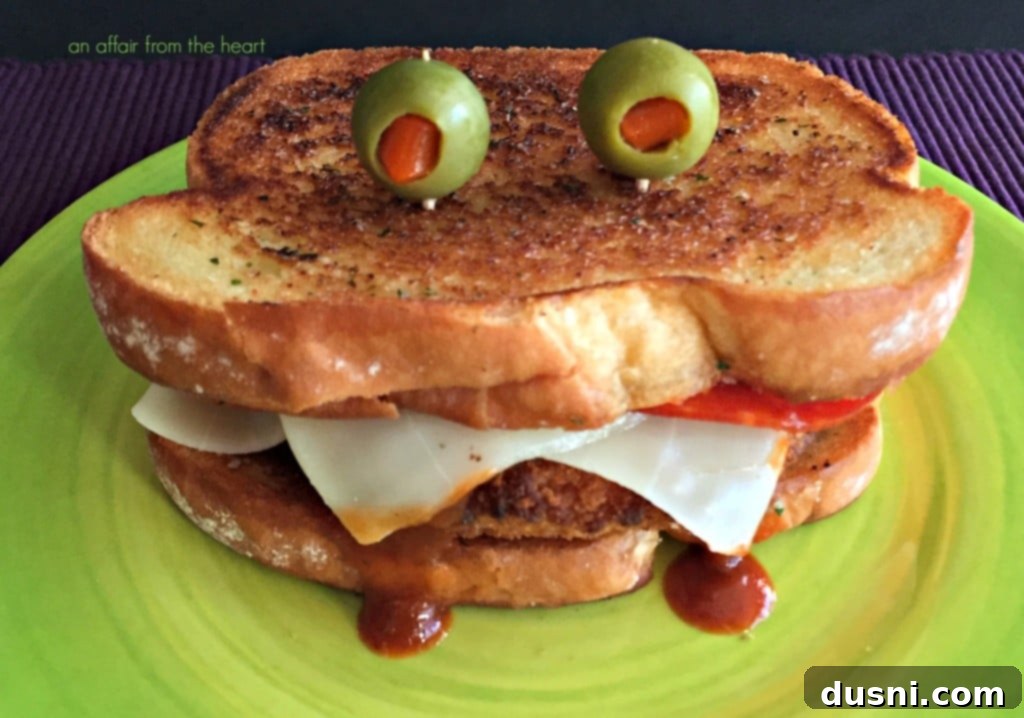 A plate with two Pizza Monster Sandwiches, garnished with a side of marinara sauce