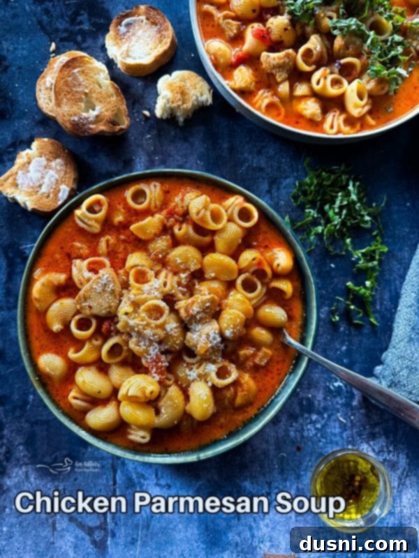 A final hero shot of creamy chicken parmesan soup in a bowl with bread and basil