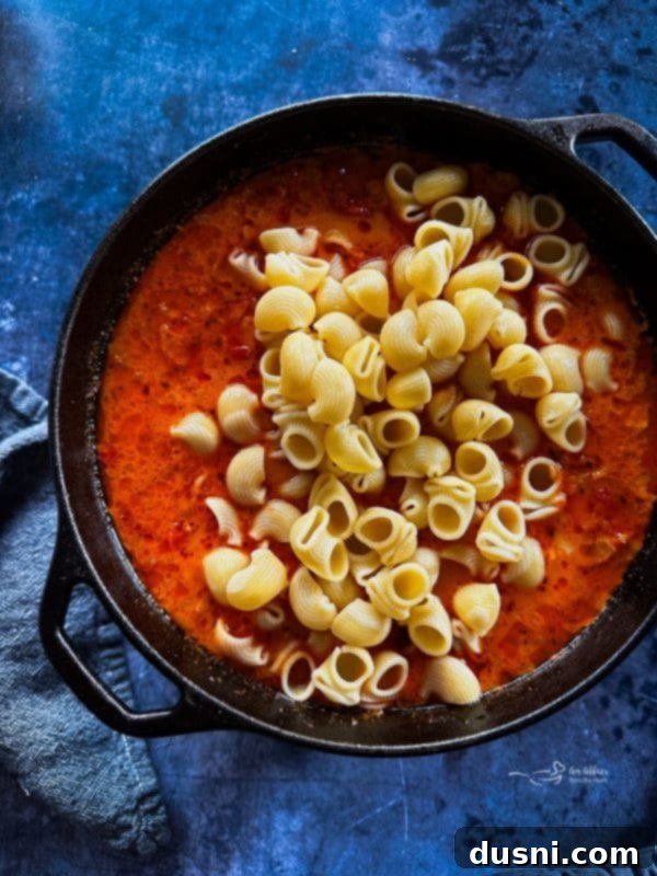 Step 3: Stirring in heavy cream and cooked pasta to the soup