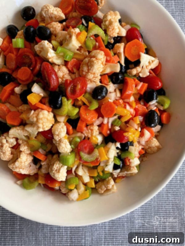 Zesty Marinated Veggies 18 Overhead shot of Mom's Marinated Vegetables in a white bowl, with a serving spoon.