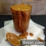 Luscious Homemade Salted Caramel 2 caramel sauce in a jar and dripping off the sides on to parchment paper with a spoon covered in the sauce. Text "homemade salted caramel sauce"