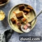 Indulgent Cream of Reuben Soup 17 Cream of Reuben Soup in a green rimmed pottery bowl with rye croutons and spoonful of soup