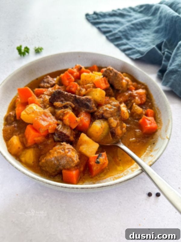 Mulligan Stew with tender beef chunks, carrots, and potatoes in a rich broth, served in a rustic bowl.