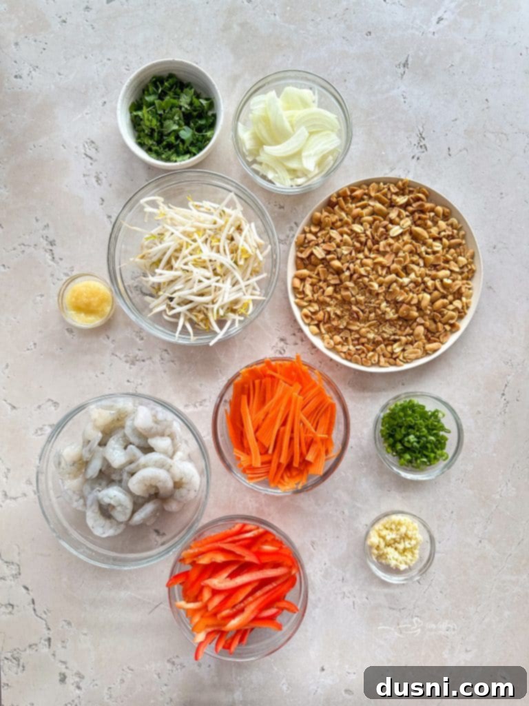 Various fresh ingredients for Pad Thai laid out on a cutting board, including shrimp, vegetables, and limes.