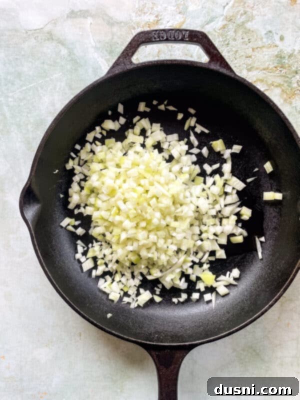 Diced onions cooking in a large skillet with olive oil, softening for the meatball mixture