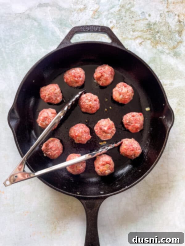 Browned Swedish meatballs resting on a paper towel-lined plate after being seared