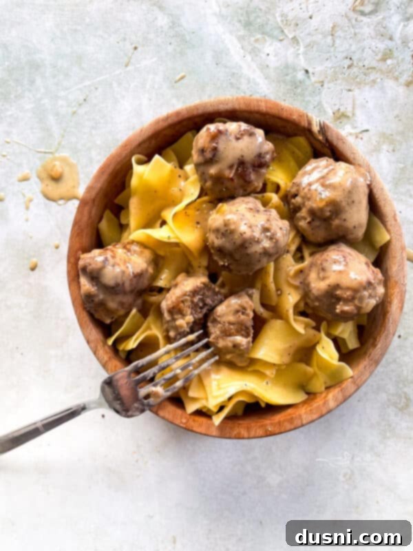 A plate of Swedish meatballs and egg noodles, garnished with fresh dill, ready to be enjoyed