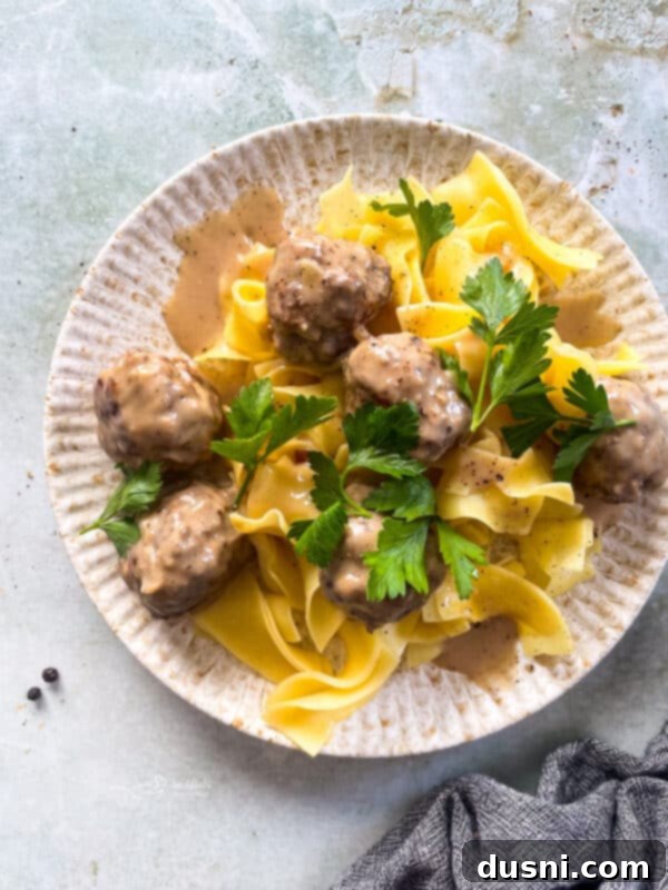 A single Swedish meatball on a spoon, showing its tender texture and creamy coating