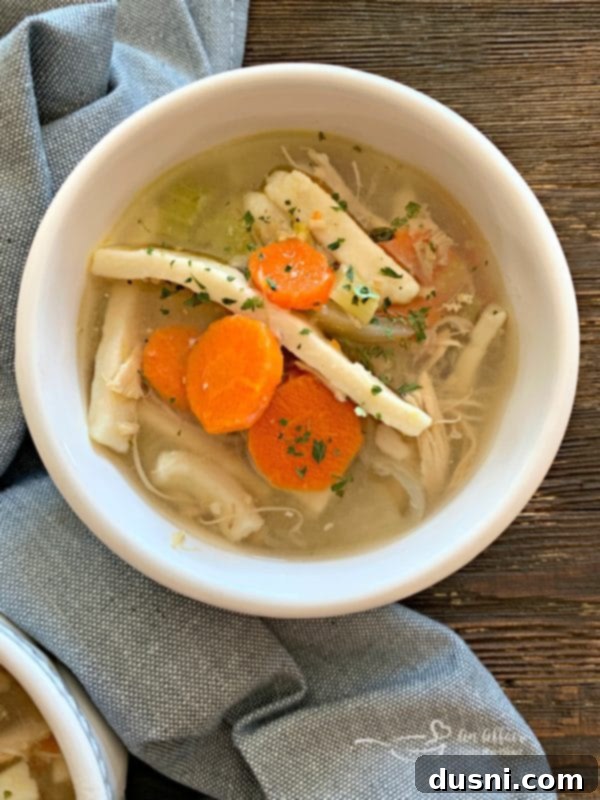 Overhead shot of a bowl of Turkey Noodle Soup with a spoon, showing the noodles, turkey, and veggies.