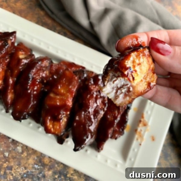 Close up of a Slow Cooker Dr. Pepper BBQ Rib with a bite taken out, showing its tenderness