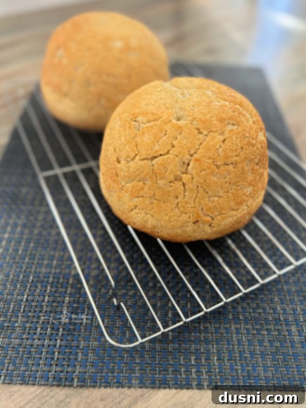 Peasant-Style Bread Two golden-brown loaves of freshly baked peasant bread cooling on a wire rack after being removed from Pyrex bowls.