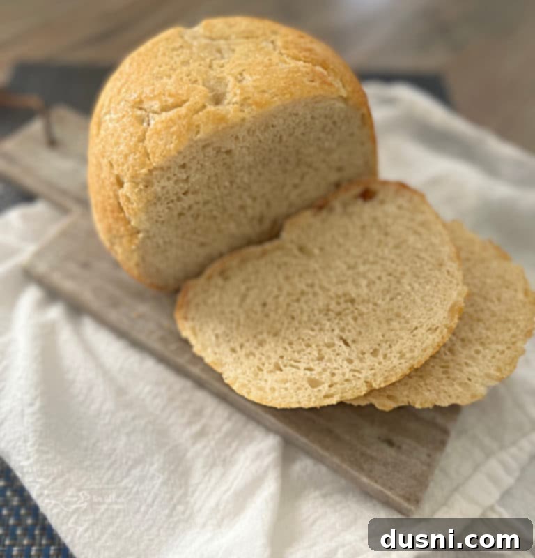Rustic Farmhouse Loaf 2 Golden-brown peasant bread loaf with a slice removed, showcasing the airy, soft crumb and crusty exterior.
