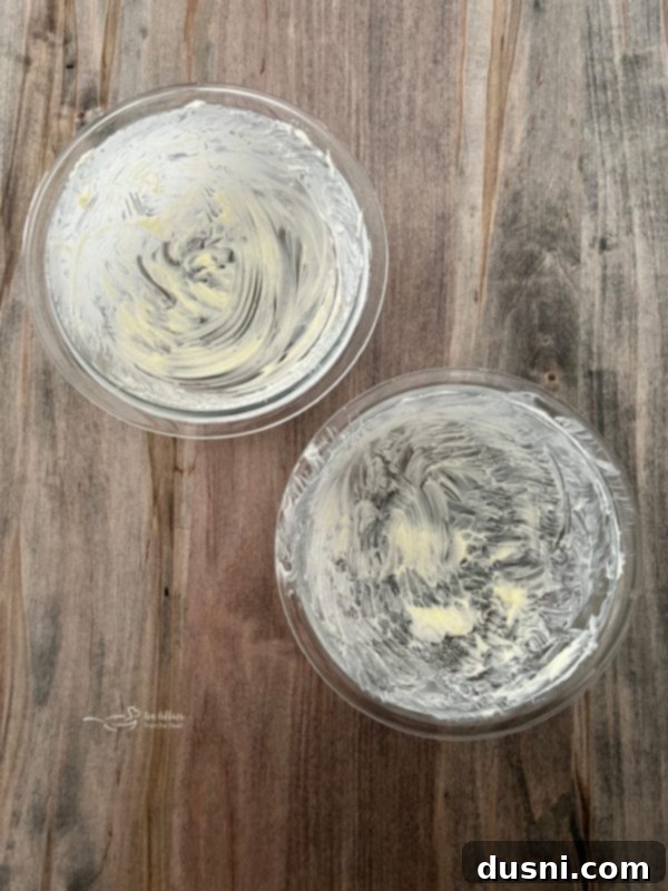 Simple Peasant Bread Recipe Two clear Pyrex bowls generously greased with softened butter, ready to receive the divided peasant bread dough.