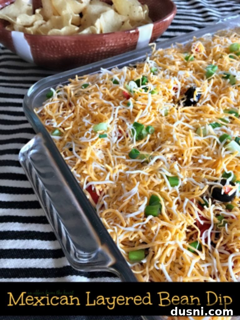 Delicious Mexican Layered Bean Dip served with tortilla chips, perfect for parties