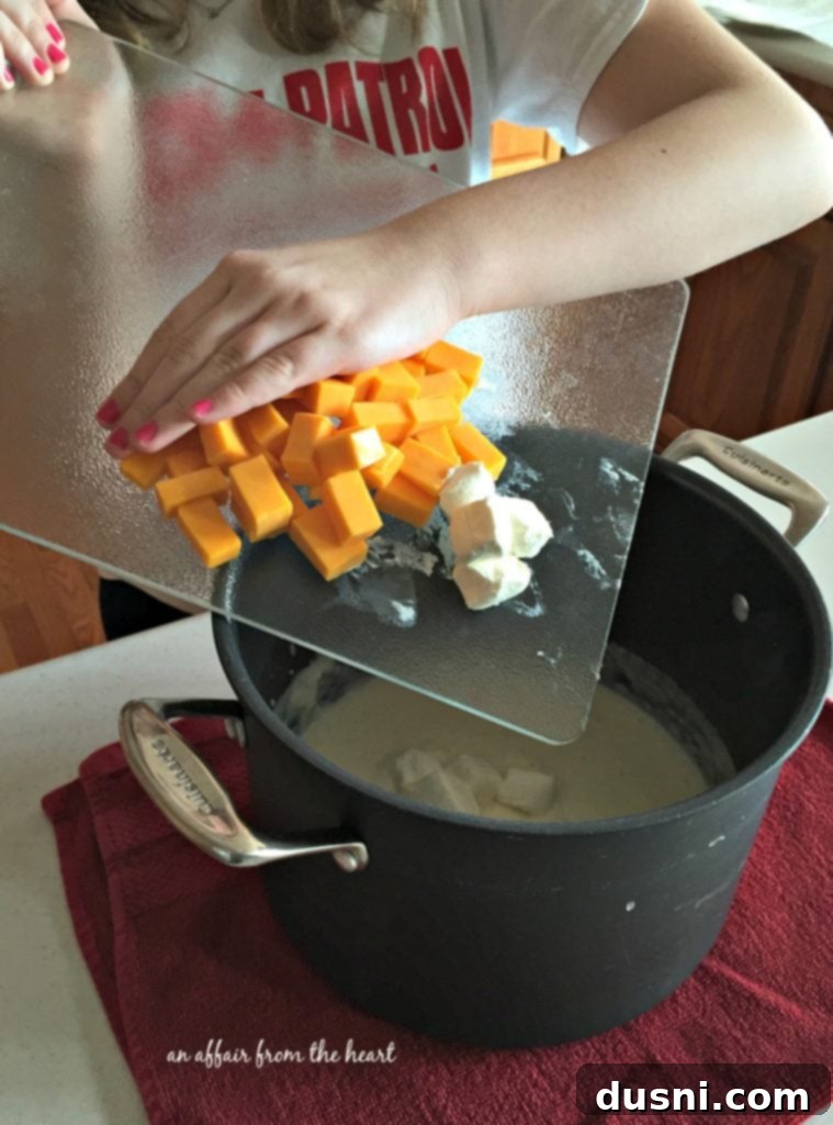 Ingredients for Loaded Mac 'n Cheese prepped on a kitchen counter, including pasta, cheeses, butter, and spices