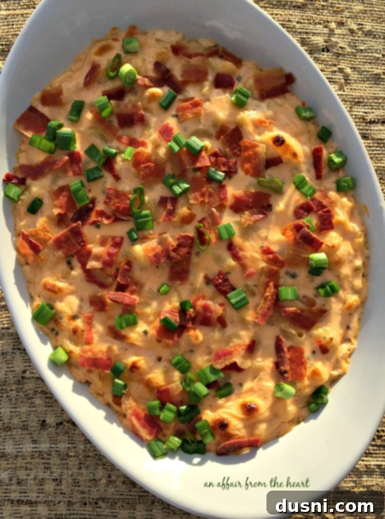 Large portion of freshly baked Loaded Mac 'n Cheese in a casserole dish with a serving spoon, ready for family dinner