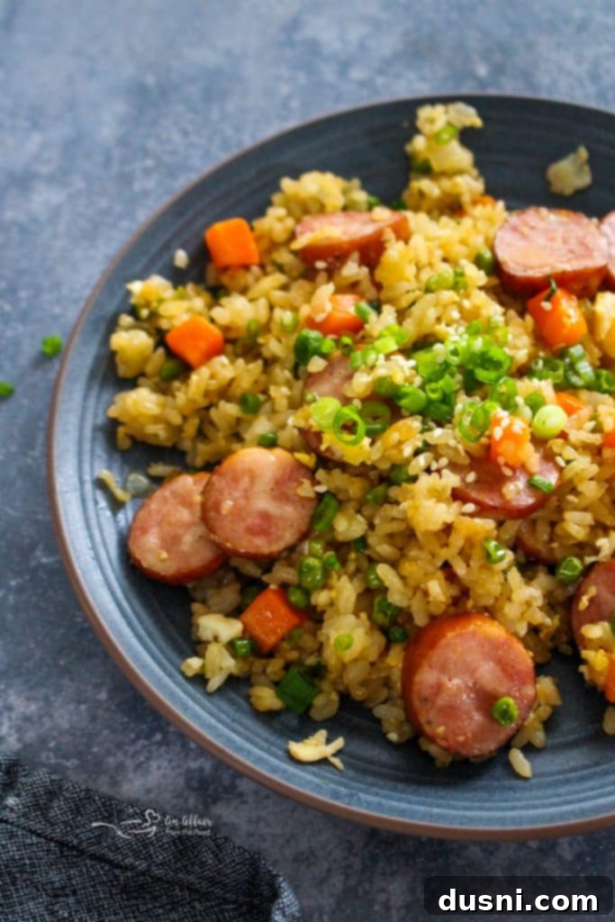 Hearty Kielbasa Fried Rice 5 A large serving spoon scooping Kielbasa Fried Rice from a skillet