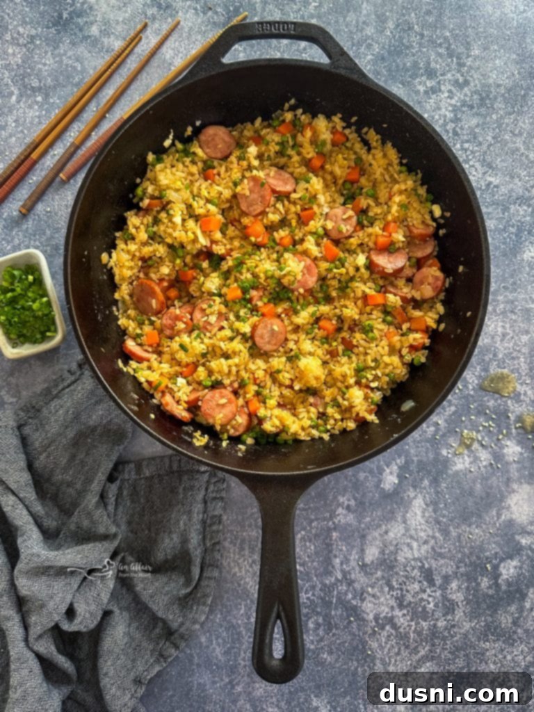 Hearty Kielbasa Fried Rice 9 Kielbasa Fried Rice garnished with sliced green onions in a pan, ready to serve