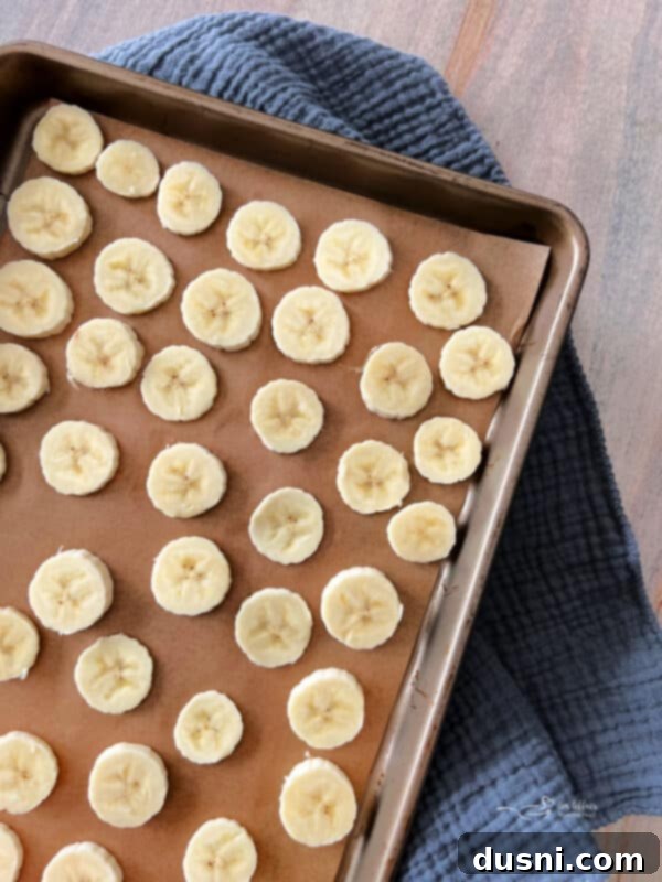 Two hands holding a half-peeled ripe banana, showing how to prepare it for freezing.