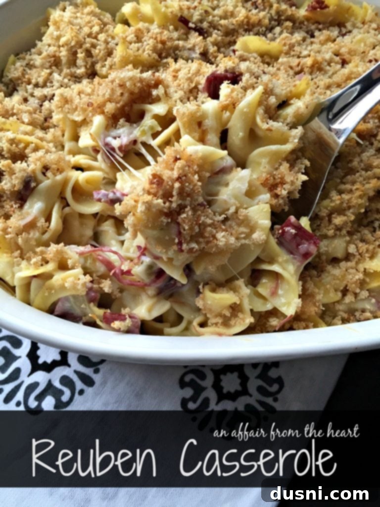 Close-up of a serving of creamy Reuben Casserole with visible wide egg noodles, tender corned beef, melted Swiss cheese, and a golden rye breadcrumb topping
