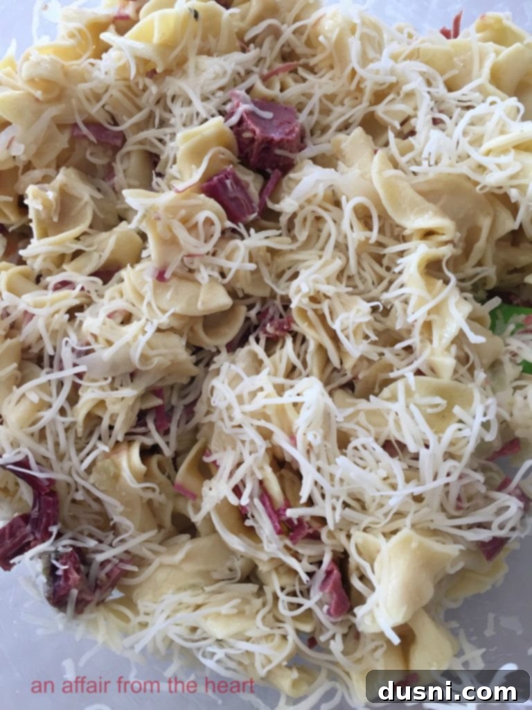 Close-up of Reuben Casserole ingredients mixed in a bowl: wide egg noodles, chopped corned beef, drained sauerkraut, and shredded Swiss cheese, ready for the creamy sauce